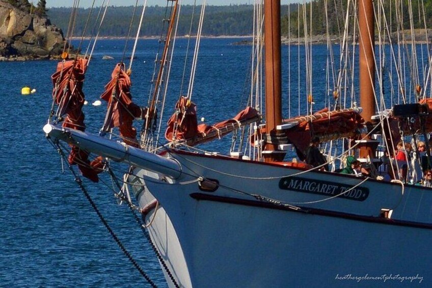 A sailboat named 'Margaret Wood' docked at a harbor with rocky shoreline and calm water. 4