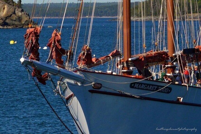 A sailboat named 'Margaret Wood' docked at a harbor with rocky shores and trees in the background. 5