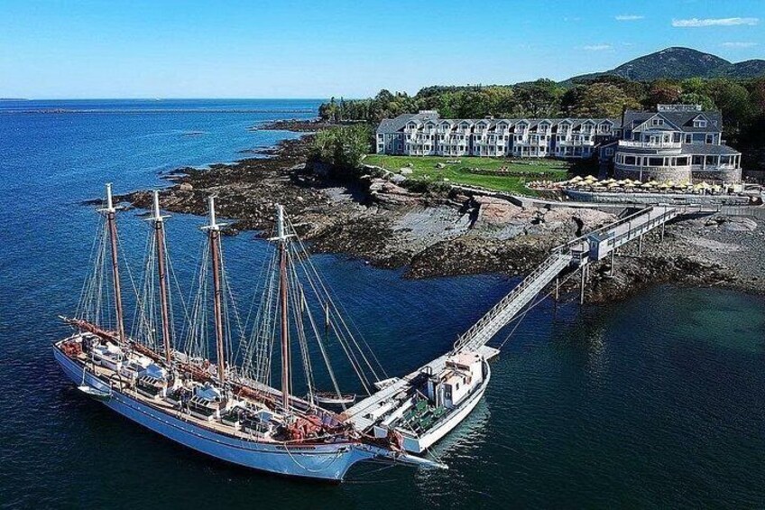 A large sailing ship docked at a pier, a coastal house, and a mountainous landscape in the background. 3