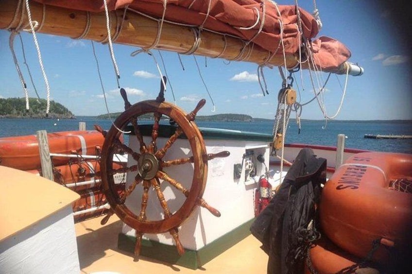 A wooden ship wheel, life buoys, and a calm sea with a distant island. 5