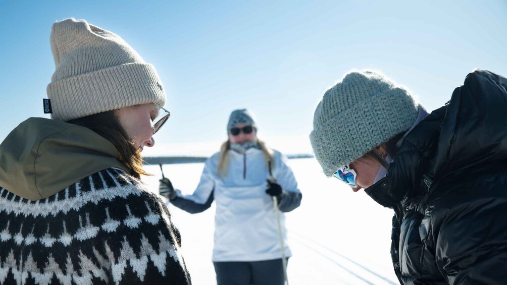 Three people in winter clothing, one wearing a white jacket, standing on a snowy surface with a clear sky in the background. 5