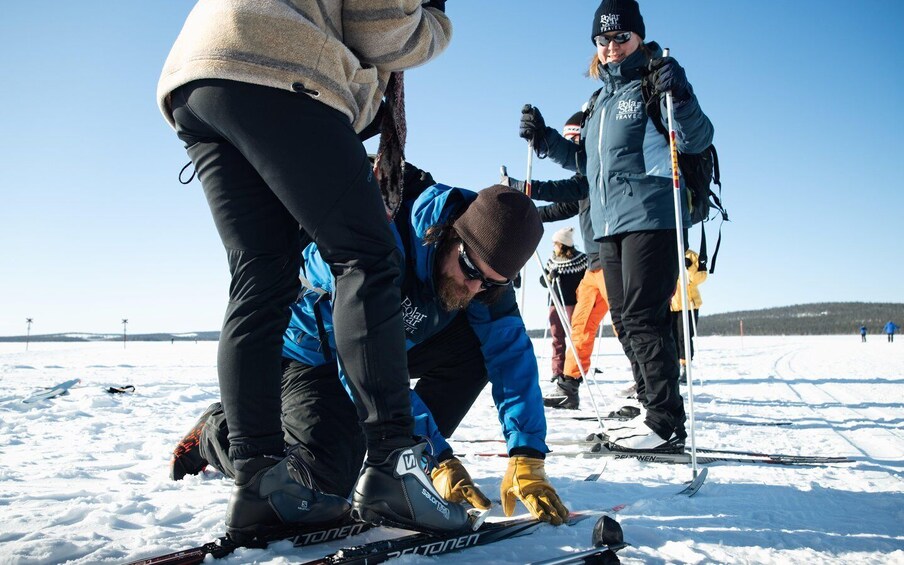People preparing skis on a snowy surface. 4
