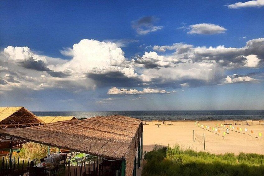 Ein Strand mit strohgedeckten Gebäuden, einem sandigen Ufer und einem teilweise bewölkten Himmel. 2