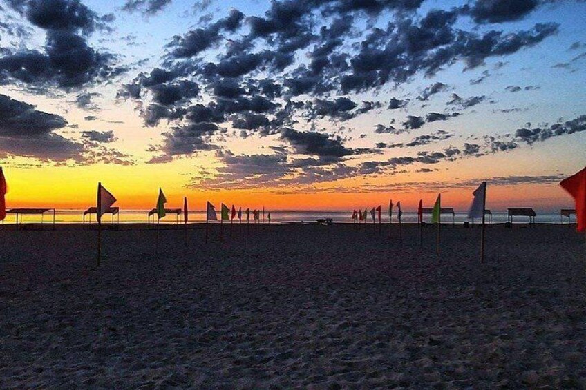 Ein Strand bei Sonnenuntergang mit Flaggen und einem Sonnenuntergang im Hintergrund. 5