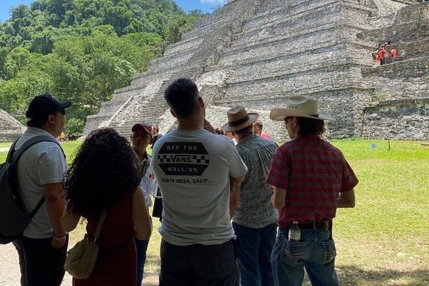 Un grupo de personas de pie frente a una gran pirámide antigua. 5