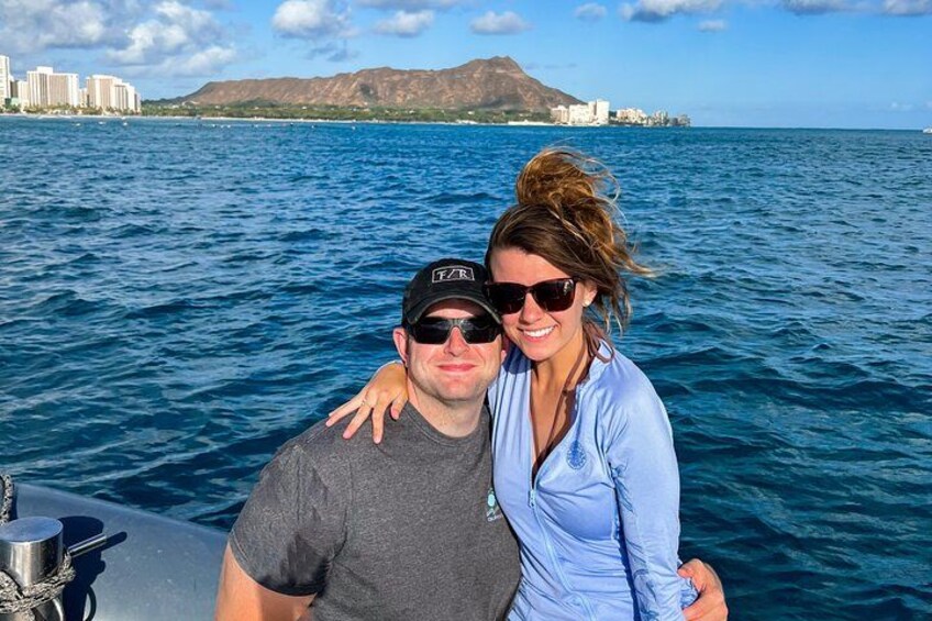 A couple on a boat with a cityscape and mountains in the background. 4