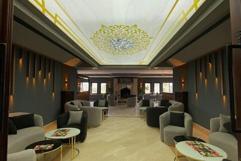 Un salon moderne avec des canapés et des tables, un plafond décoratif et une cheminée en arrière-plan. 1