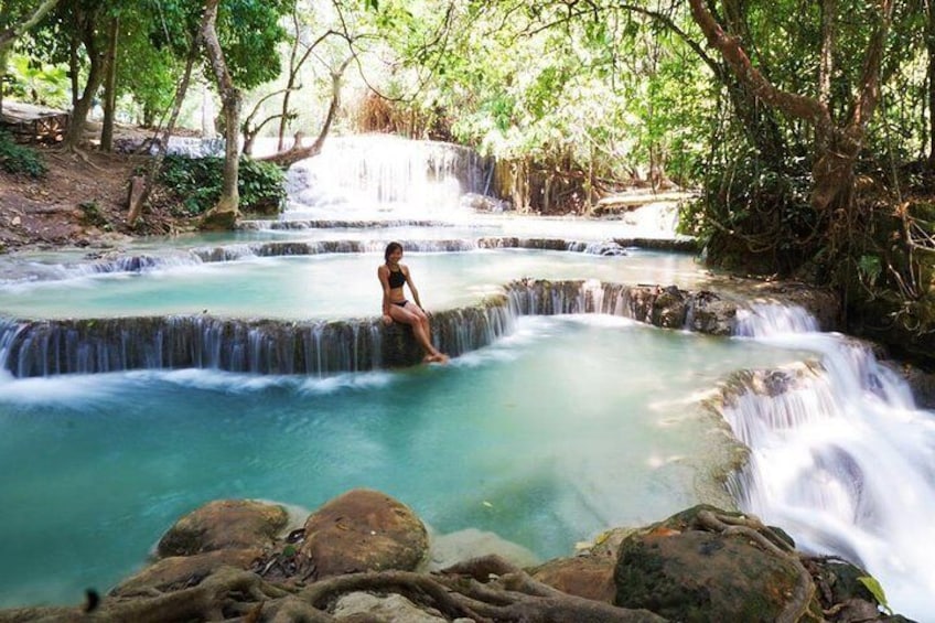 Una mujer sentada sobre una roca en una cascada natural. 5