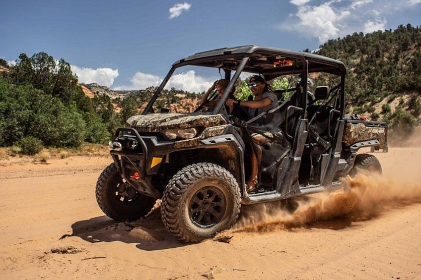 A black off-road vehicle driving on a sandy terrain with a person in the driver's seat. 3