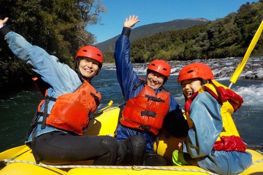 Tres personas en un bote amarillo sobre un río, usando chalecos salvavidas y cascos. 5
