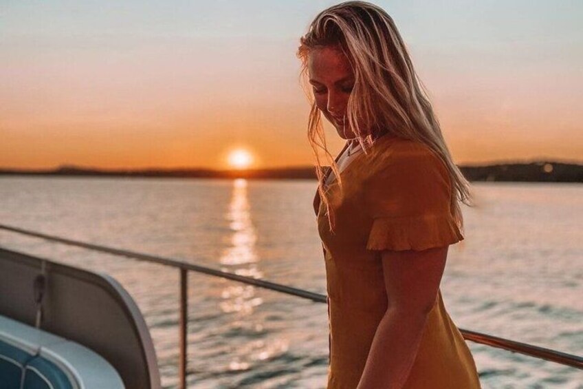 A person standing on a boat with a sunset in the background. 2