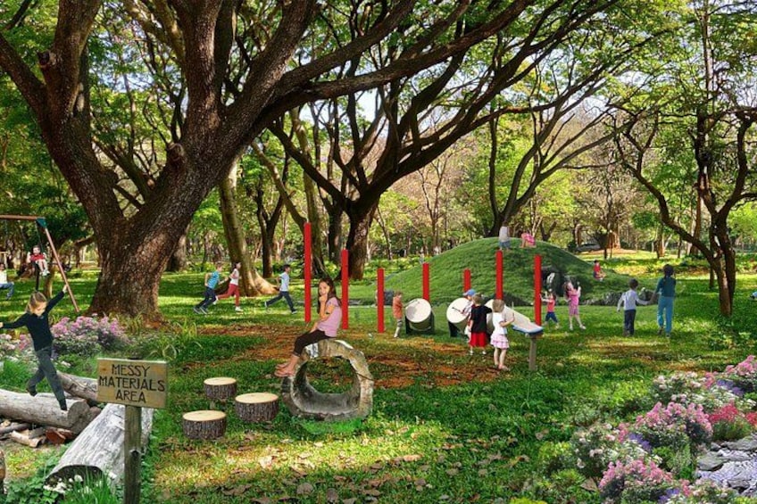 A park with a large tree, a grassy area, and a sign that reads 'MATERIALS AREA.' 1