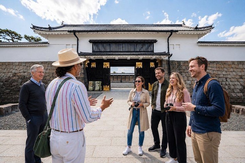 A group of people standing in front of a traditional building with a tiled roof and a stone wall. 1