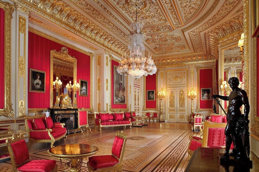 An opulent room with red and gold decor, ornate chandeliers, and classical statues. 4