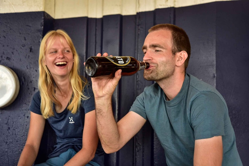 Two people sitting, one holding a bottle. 3