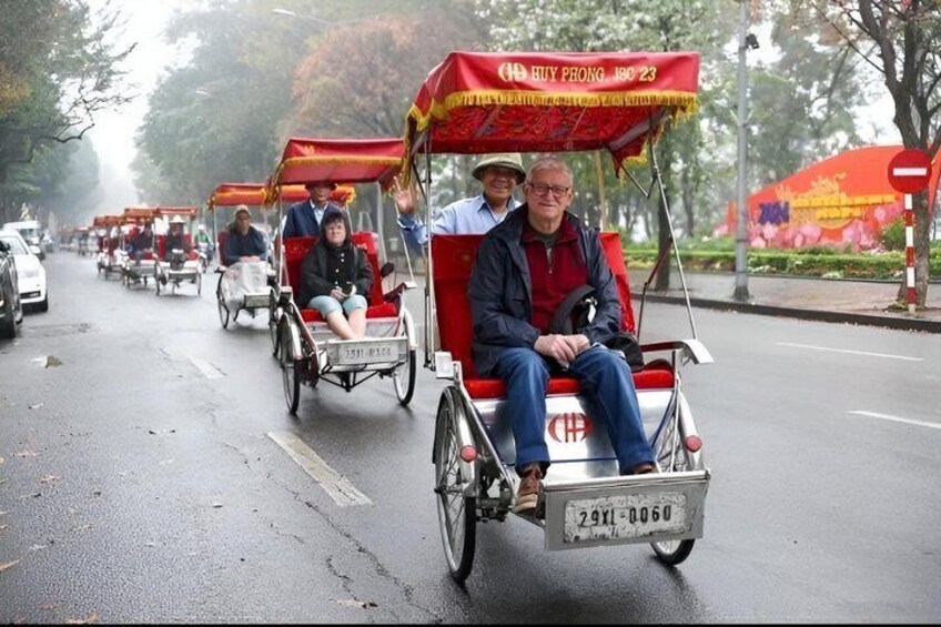 A group of people riding rickshaws on a wet road. 1