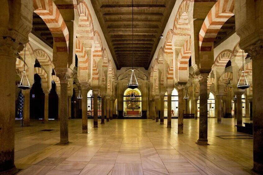 A spacious interior with high arches and columns, featuring a central stained glass window. 2