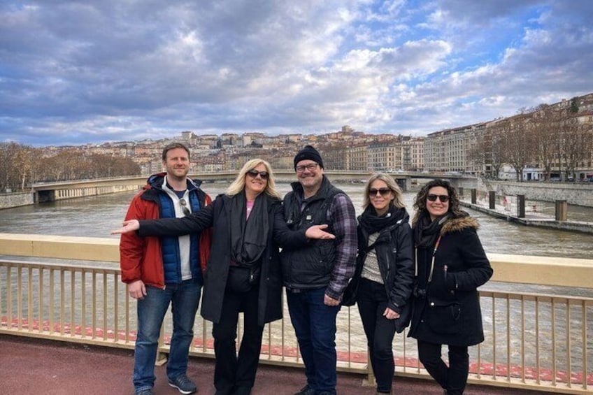 A group of people standing by a river with a cityscape in the background. 2