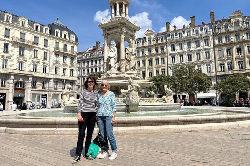 Two people standing in front of a historic fountain with ornate sculptures, surrounded by classical architecture. 4