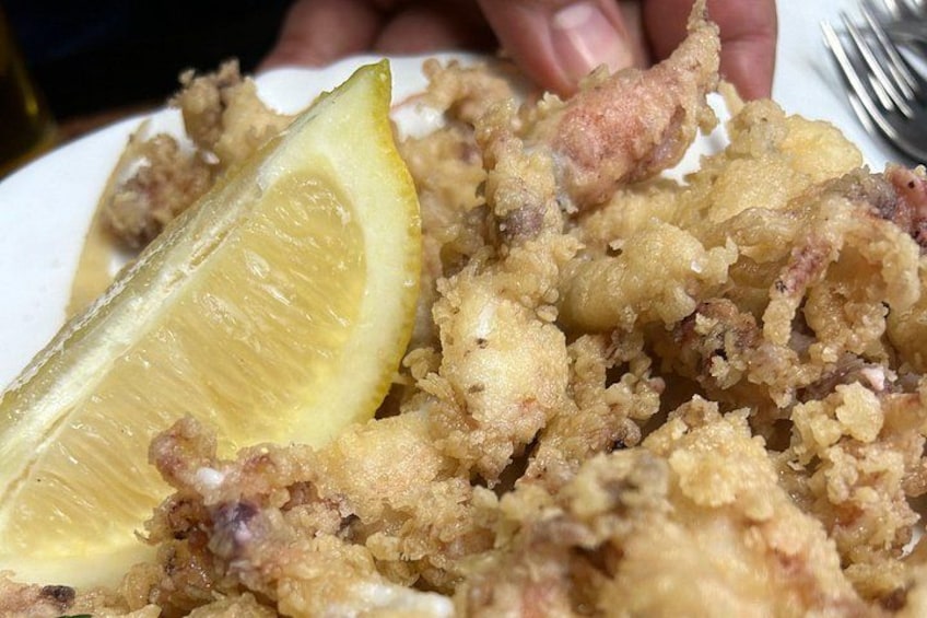 Ein Teller mit frittiertem Essen und einem Zitronenschnitz. 4