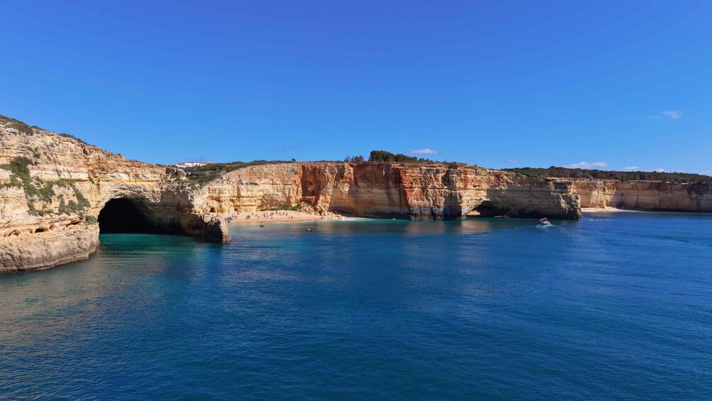 A coastal landscape with a prominent rock formation, a beach, and clear blue waters. 2
