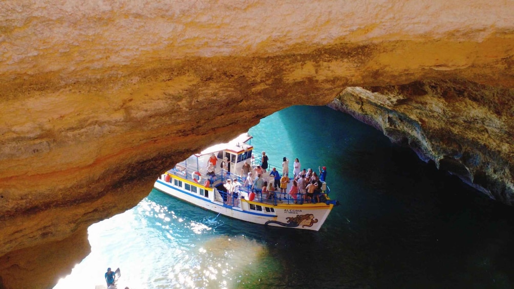 Un bateau avec des personnes à bord, partiellement à l’intérieur d’une grotte. 1