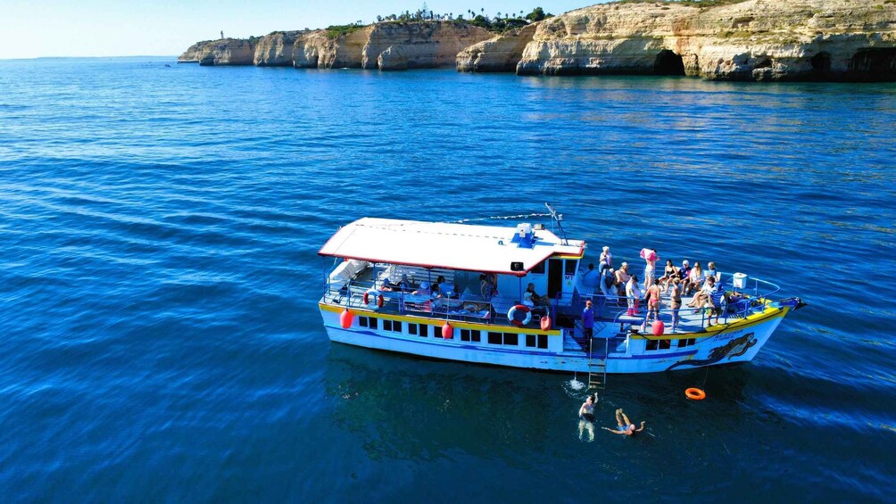 A boat with passengers on a clear day, surrounded by calm blue waters and rocky cliffs. 5