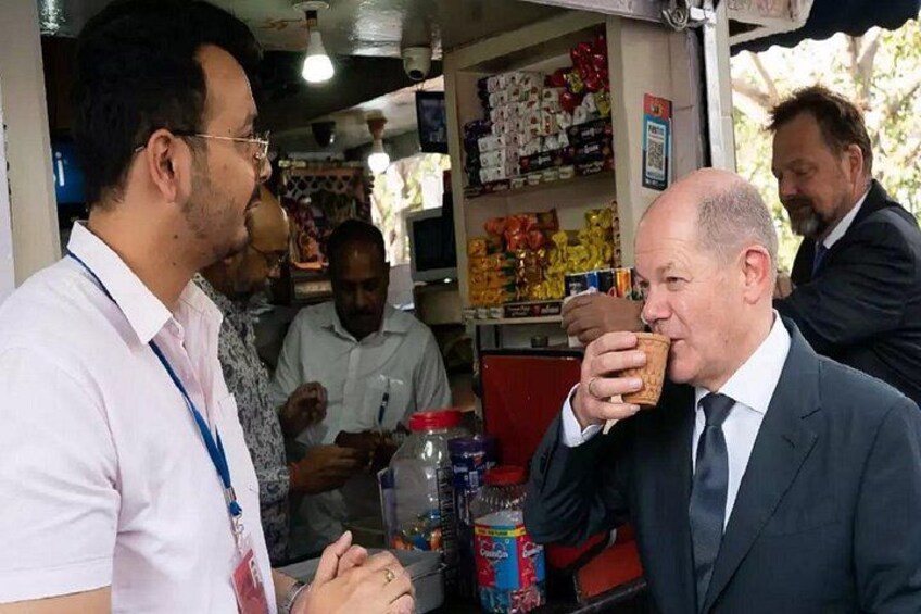 A man in a suit eating a snack, another man in a white shirt, and a third man in a patterned shirt. 4