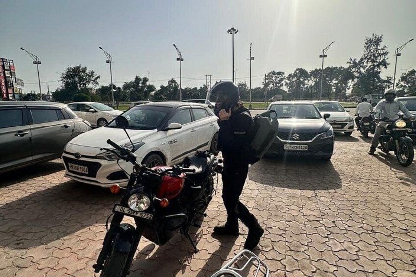 A person inspecting a motorcycle in a parking lot with cars and motorcycles around. 5