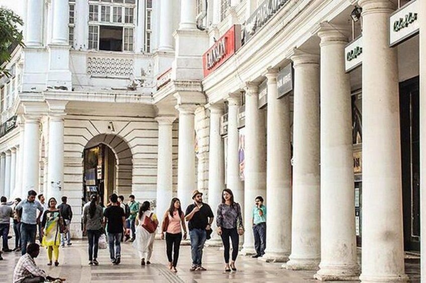 A busy street with people walking, a building with columns, and a sign that reads 'Café'. 2