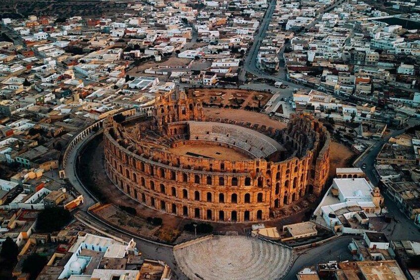 A large, circular ancient amphitheater surrounded by a densely packed urban area. 1