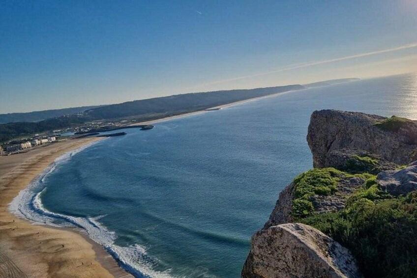 A coastal landscape with a beach, ocean, and rocky cliffs. 2