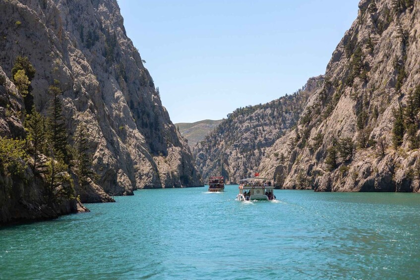 A boat on a turquoise river surrounded by steep, rocky cliffs. 3