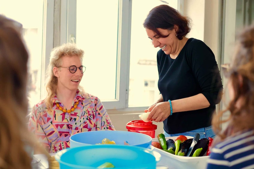 A woman squeezing juice from a lemon into a red container, with a bowl of vegetables and a blue bowl on the table. 1