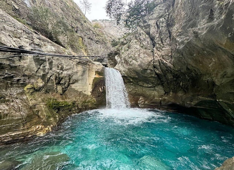 A waterfall flowing into a turquoise pool surrounded by rocky cliffs. 1
