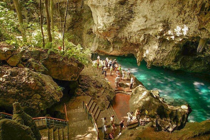 Una cueva con un estanque de agua, formaciones rocosas y un grupo de personas. 4