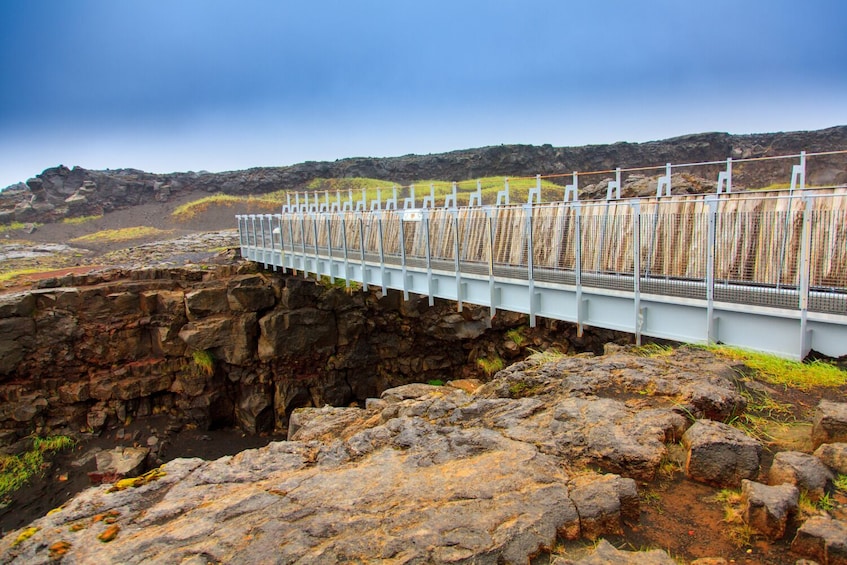 A bridge over a rocky gorge with a metal railing. 5