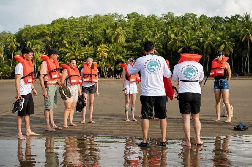 Eine Gruppe von Menschen am Strand, die Rettungswesten tragen und Surfbretter halten. 2