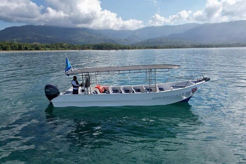 Ein weißes Boot mit blauer Segel auf ruhigem Wasser, umgeben von Bergen und wolkenlosem Himmel. 1