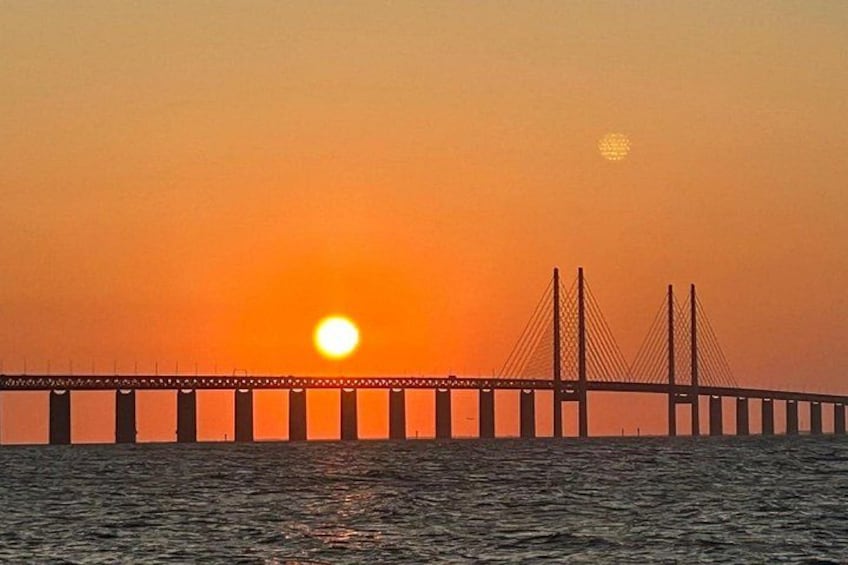 A bridge with multiple cables and towers during sunset. 2