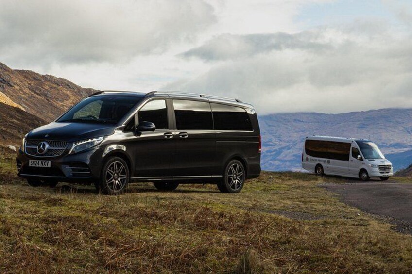A black Mercedes-Benz Sprinter van parked on a grassy field with mountains in the background. 5
