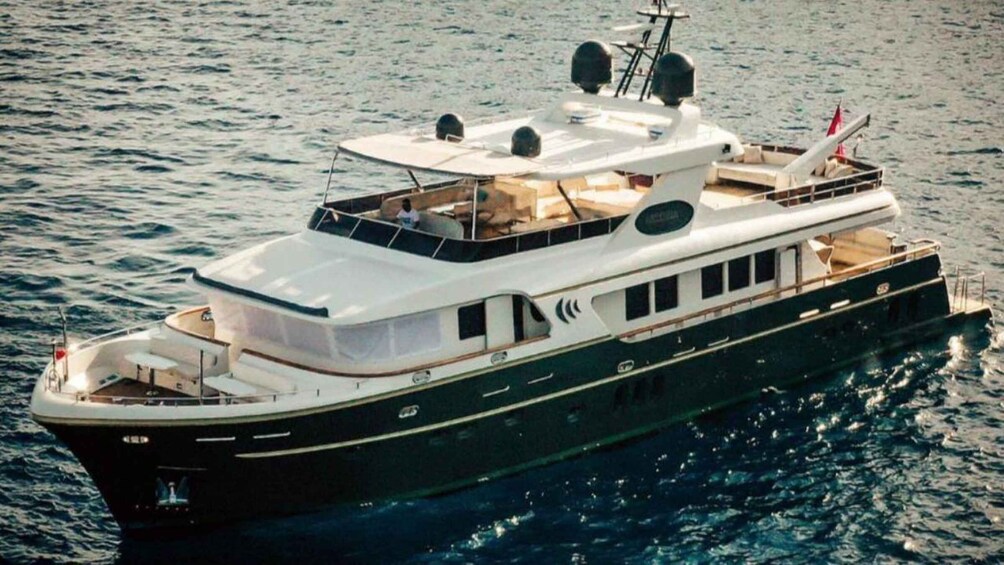 A large, multi-deck yacht with a white superstructure and a black hull, sailing on calm waters. 4