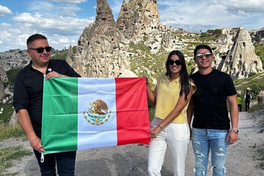 A group of people holding a flag, standing in front of a rocky landscape with unique rock formations. 2