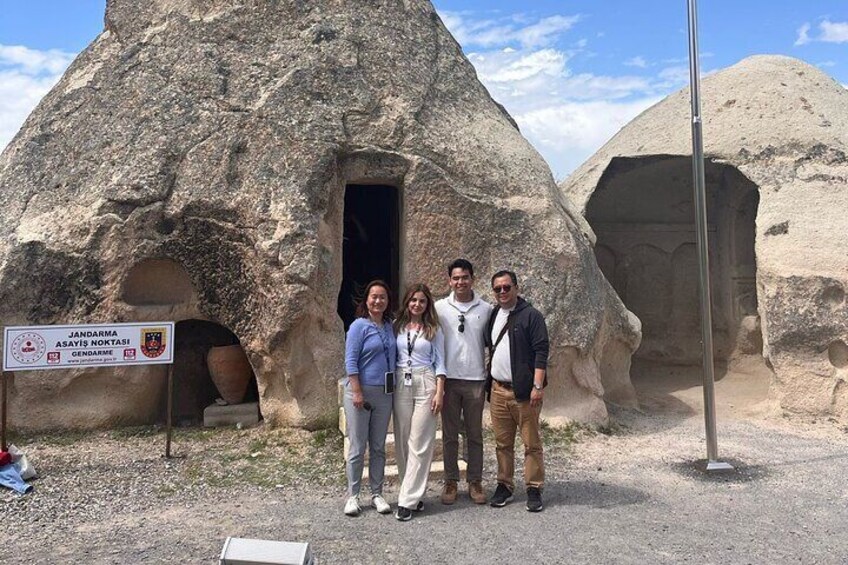 A group of people standing in front of a large, conical rock formation with a door. 5