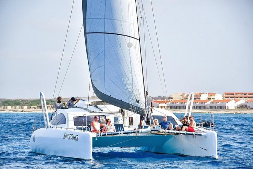 A sailboat named 'KINGSFISHER' on the water with people on deck. 5