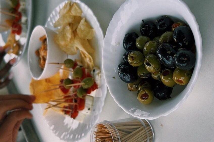 A table with bowls of olives and chips, and skewers with cheese and vegetables. 3