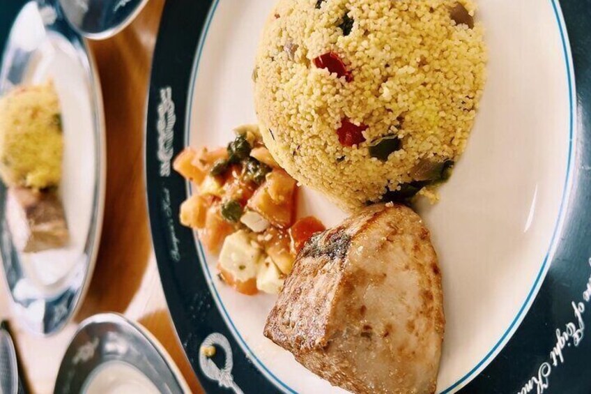 Ein Teller mit Couscous, gegrilltem Fleisch und einem Gemüsebeilagen. 3