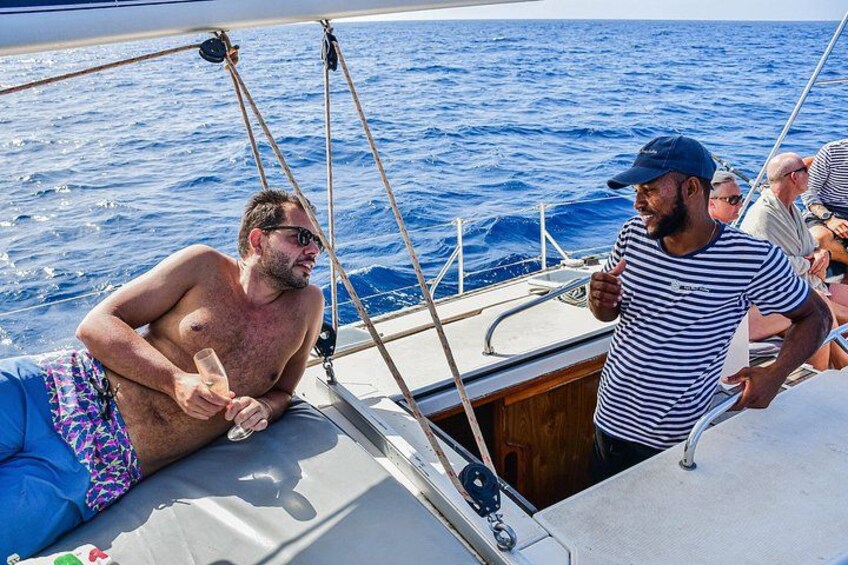A sailboat with people on deck, a man giving a thumbs-up, and a man in a striped shirt. 2