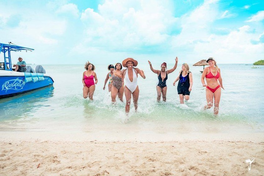 A group of people in swimsuits on a beach with a boat in the background. 3