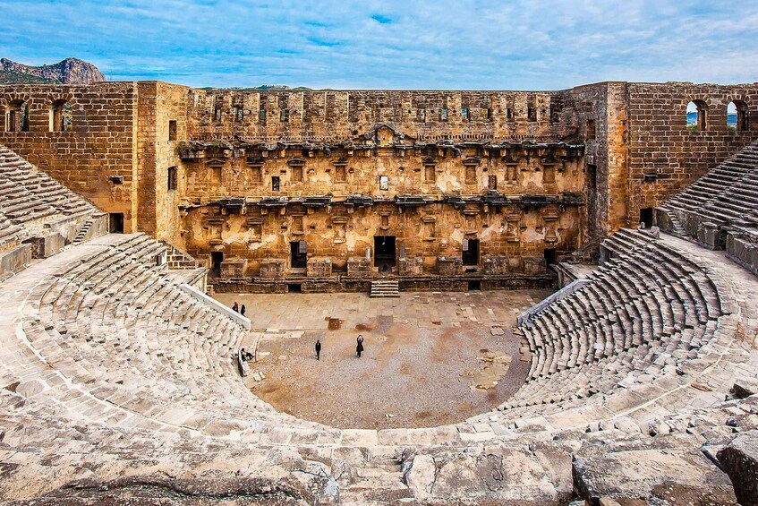 An ancient amphitheater with stone seating and a central stage. 3